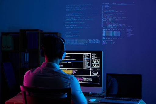 man sitting in from of a computer and checking code